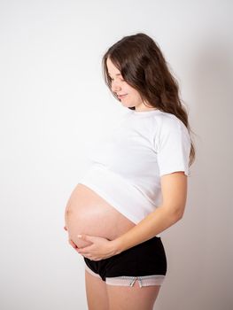 The young beautiful pregnant woman experiences strong emotions on a white background.