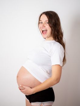 The young beautiful pregnant woman experiences strong emotions on a white background.