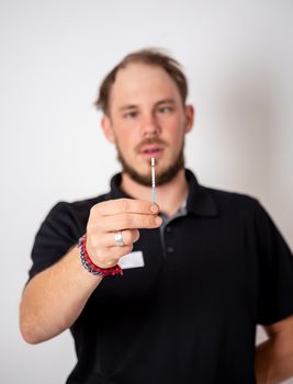 Positive pregnancy test held by a surprised man in the background.