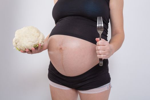 Pregnant woman holding glass bowl with fresh salad