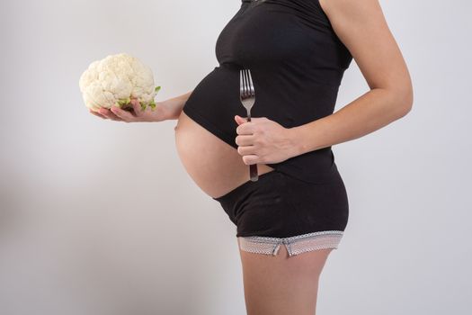 Pregnant woman holding glass bowl with fresh salad