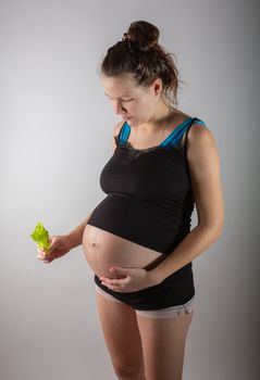 Pregnant woman holding glass bowl with fresh salad