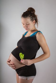 Pregnant woman holding glass bowl with fresh salad