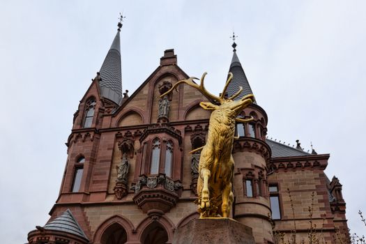 Konigswinter, Germany - 2 March 2019: Drachenburg castle on a gloomy day with a statue of golden deer