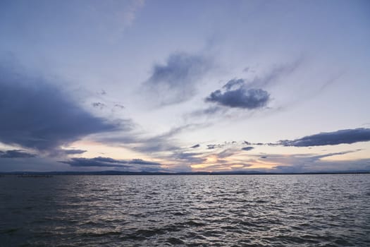 Landscape of a lake with storm clouds, moving waters reeds in the water, bluish tones