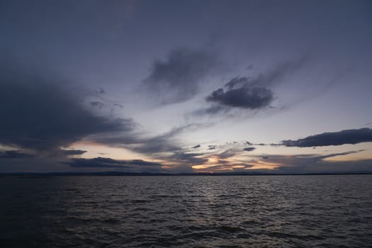 Landscape of a lake with storm clouds, moving waters reeds in the water, bluish tones