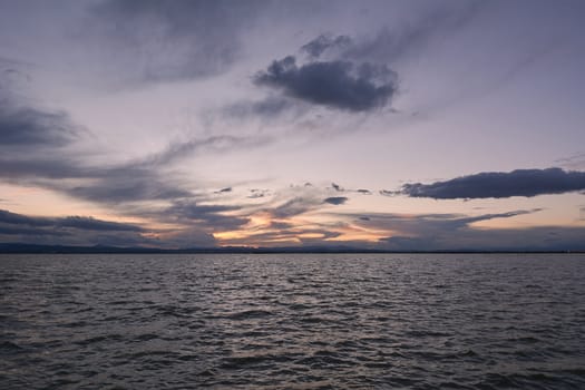 Landscape of a lake with storm clouds, moving waters reeds in the water, bluish tones