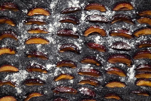 food background plum poppy seed cake on black pan