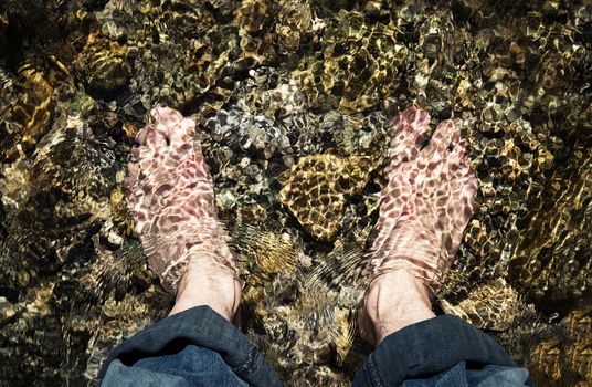 seasonal nature background bare feet in a cold mountain stream