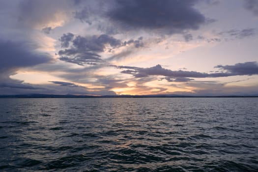 Landscape of a lake with storm clouds, moving waters reeds in the water, bluish tones