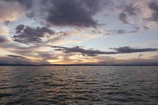 Landscape of a lake with storm clouds, moving waters reeds in the water, bluish tones