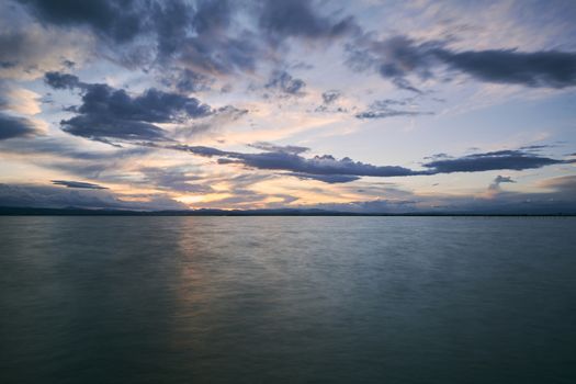 Landscape of a lake with storm clouds, moving waters reeds in the water, bluish tones, long exposure, silk effect