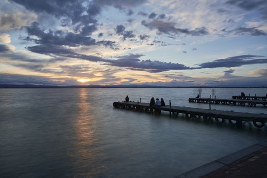 Landscape of a lake with storm clouds, moving waters reeds in the water, bluish tones, pier, long exposure, silk effect