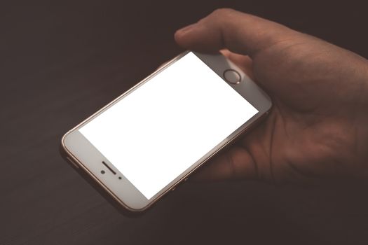 Closeup of male hand holding and using modern smart phone with blank screen for your text or content