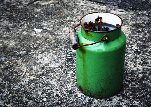 an old green tin-filled kettle filled with rusty nails