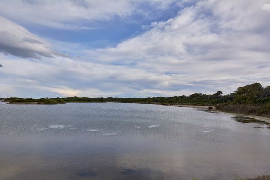 Lake with calm waters after the storm, dramatic clouds, blue sky and reflections in the water