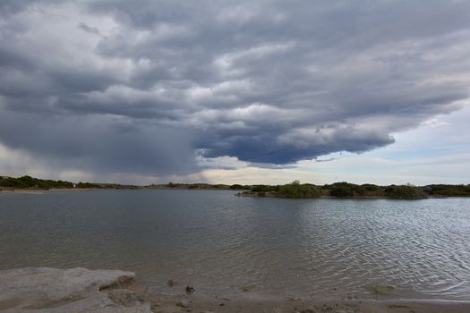 Lake with calm waters after the storm, dramatic clouds, blue sky and reflections in the water