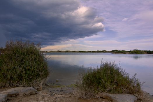 Lake with calm waters after the storm, dramatic clouds, blue sky and reflections in the water