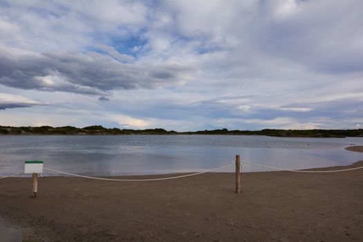 Lake with calm waters after the storm, dramatic clouds, blue sky and reflections in the water