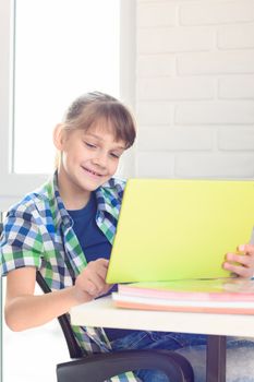 Girl studying in a tablet computer while sitting at a table at home