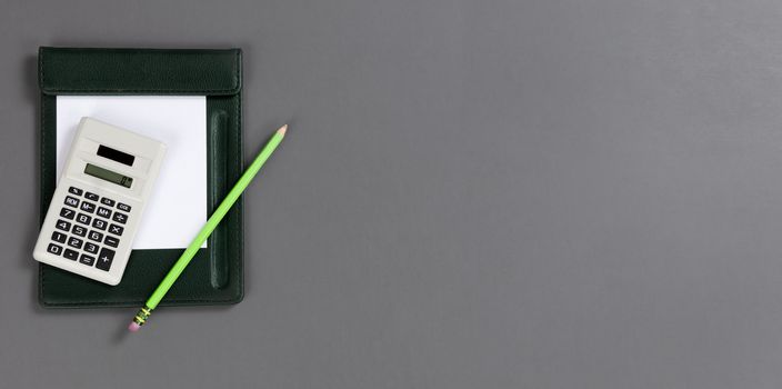 Small calculator with traditional paper and pencil on a gray table top with copy space 