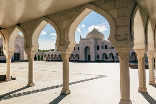 View of the white mosque in the sunset light through the Arches. Bolghar, Russia