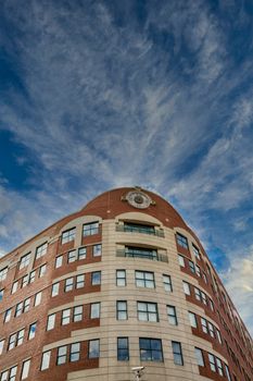 Clock at the top of a beautiful curved brick office building under nice skies