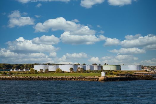 White Fuel tanks on the Canadian coast with a small lighthouse by the water