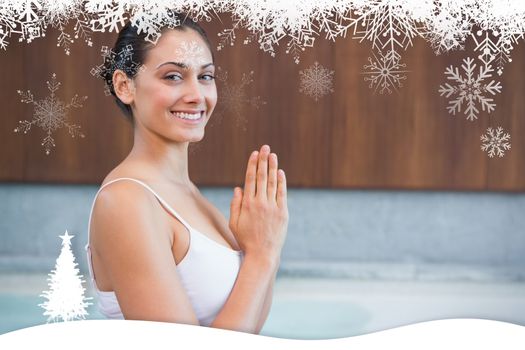 Content brunette in white sitting in lotus pose  against fir tree forest and snowflakes