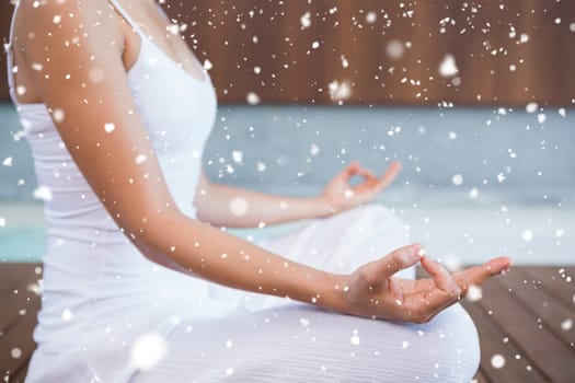 Peaceful woman in white sitting in lotus pose  against snow falling