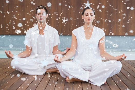Attractive couple in white meditating in lotus pose against snow
