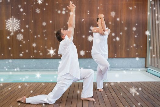 Peaceful couple in white doing yoga together against snow falling