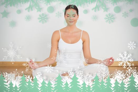 Smiling brunette sitting in lotus pose looking at camera against snowflakes and fir trees in green