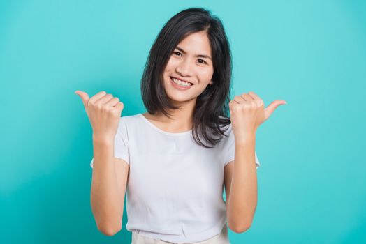 Portrait Asian beautiful happy young woman smile white teeth wear white t-shirt standing successful woman giving two thumbs up gesture, on a blue background with copy space