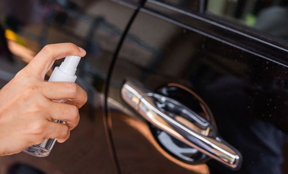 Asian young woman applying press dispenser sanitizer alcohol spray squirt to car door wash cleaning, hygiene prevention COVID-19 or coronavirus protection concept, isolated on white background