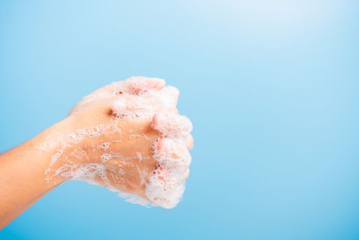Closeup body care Asian young woman washing hands with soap have foam, hygiene prevention COVID-19 or coronavirus protection concept, isolated on blue background