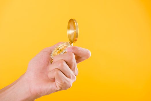 Hand holding antique brass compass isolated on yellow background with copy space for text