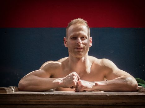 Handsome muscular young man standing in gym during workout, looking at camera