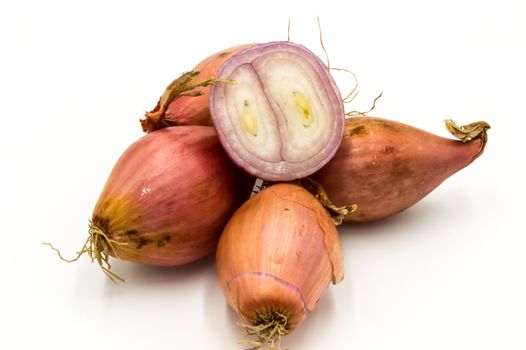 Vegetables: several isolated shallots, one cut in half on a white background