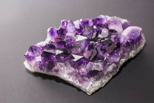 An amethyst stone placed on the dark background. Horizontal studio shot.