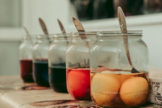 Several jars full of paint and Еaster eggs ready to be colored.