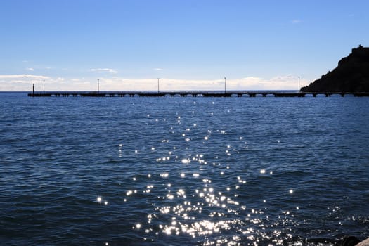 Long pier in the sea with sunshine reflection landscape.