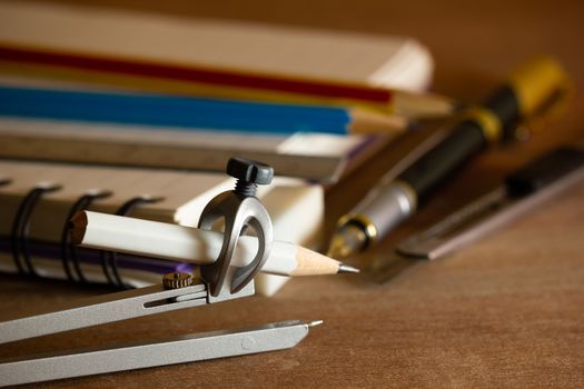 Compass for drawing and stationary on wooden table. Concept of architecture office or back to school. Closeup and copy space for text.