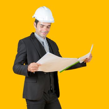 Young businessman in a gray shirt and black suit wearing a white construction hat is enjoying a progressive real estate plan. The project owner is checking the construction drawings.
