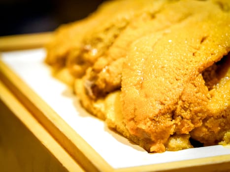 Closeup Fresh Uni. Atlantic sea urchin meat in wooden tray