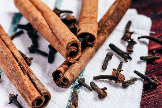 Cinnamon sticks and cloves on white kitchen towel