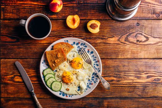 Breakfast toast with fried eggs with vegetables on plate and cup of coffee with fruits over dark wooden background, top view. Clean eating concept.