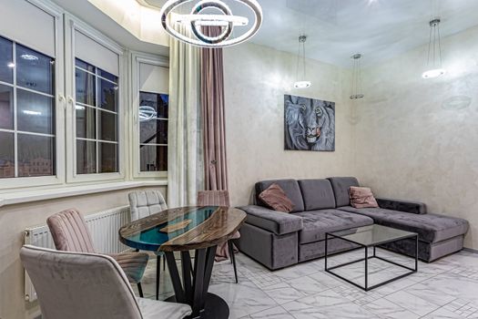 Modern interior of a large and cozy living room with a sofa and a table by the window.