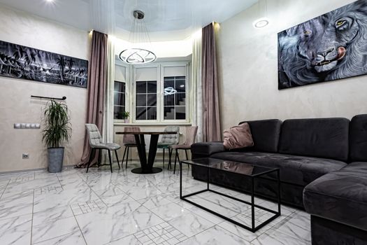 Modern interior of a large and cozy living room with a sofa and a table by the window.