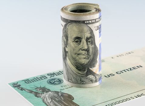 Roll of 100 dollar bills with illustrative coronavirus stimulus payment check to show the virus stimulus payment to Americans
